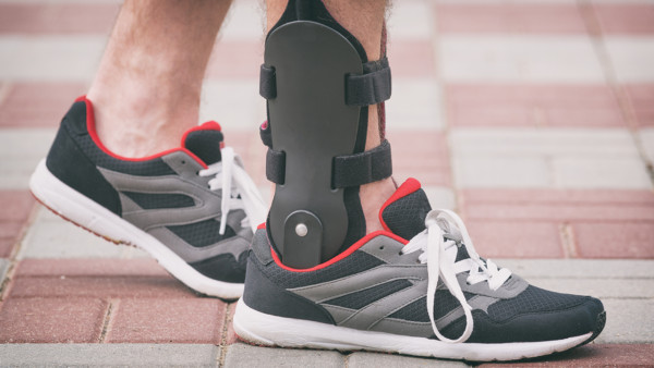 Photo of a man outdoors in athletic sneakers wearing ankle orthosis or brace