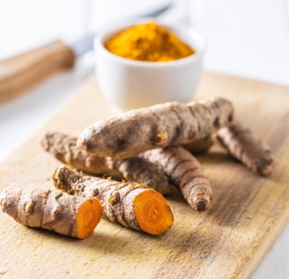 Photo of turmeric root and powder on a wooden cutting board