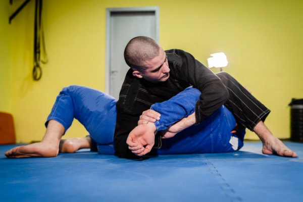  training sparring athlete fighter applying kimura shoulder lock submission on his opponent during technique practice