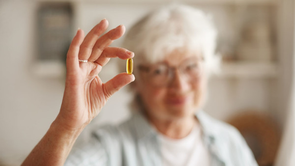 Close-up shot of an older woman's hand holding a fish oil pill